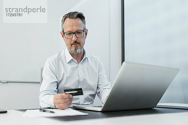 Geschäftsmann mit Laptop und Kreditkarte im Büro