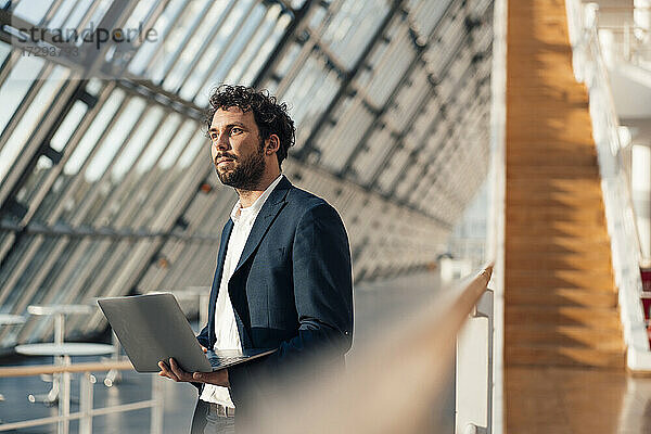 Männlicher Unternehmer mit Laptop im Büro stehend