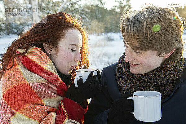 Freundin in Schal eingewickelt  während sie mit ihrem Freund Kaffee trinkt