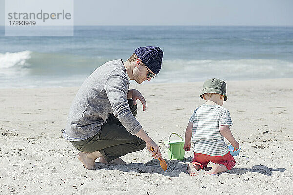 Vater und Sohn spielen mit Sandspielzeug am Strand