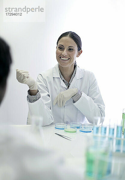 Lächelnde Laborantin bei der Arbeit mit einem Kollegen im Labor