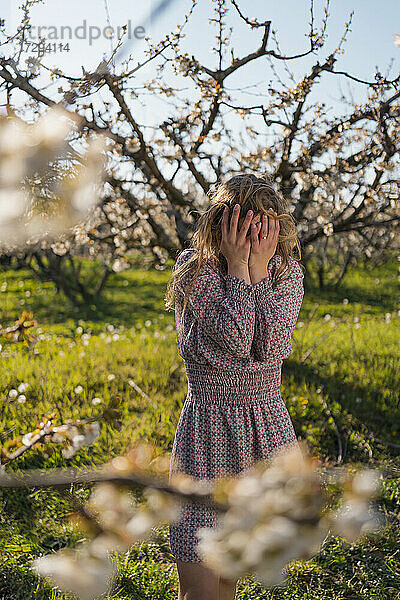 Frau mit Kopf in den Händen im Kirschgarten im Frühling