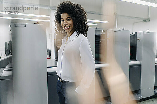 Lächelnde Geschäftsfrau vor Maschinen in der Industrie