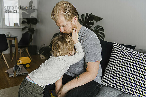 Blonder Vater küsst den Kopf des Sohnes zu Hause
