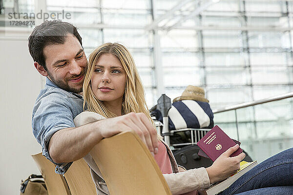 Junges Paar mit Reisepass wartet im Abflugbereich des Flughafens