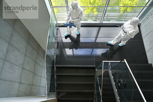 Sanitäter desinfizieren das Treppenhaus im Büro