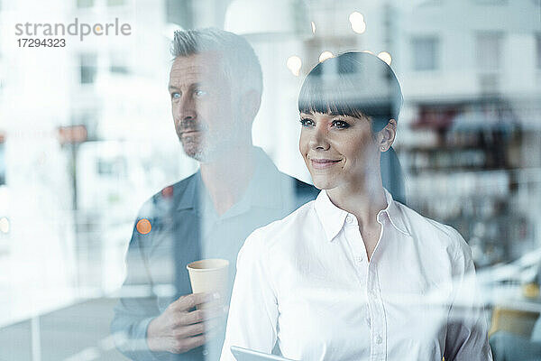 Geschäftsfrau schaut weg  während sie mit einem Kollegen im Hintergrund in einem Café steht