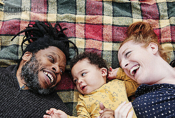 Fröhliche Familie entspannt sich mit ihrem Sohn auf einer Picknick-Decke im Park