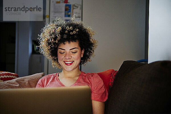 Lächelnde schöne Frau mit Laptop im Wohnzimmer zu Hause