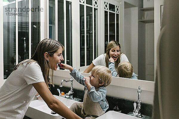 Junge beim Zähneputzen der Mutter im heimischen Badezimmer