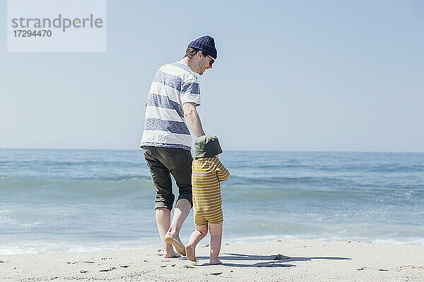 Vater und Sohn gehen am Strand zum Wasser