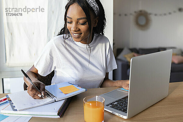 Lächelnde Geschäftsfrau  die zu Hause am Laptop schreibt