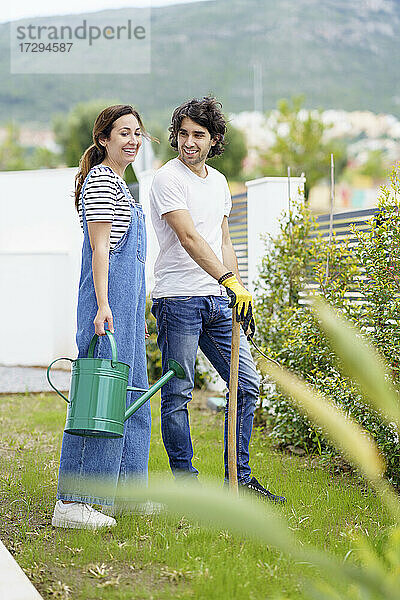 Lächelndes mittleres erwachsenes Paar im Garten stehend