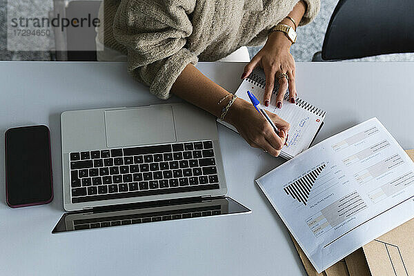Geschäftsfrau schreibt Tagebuch bei der Arbeit an Finanzdaten im Büro