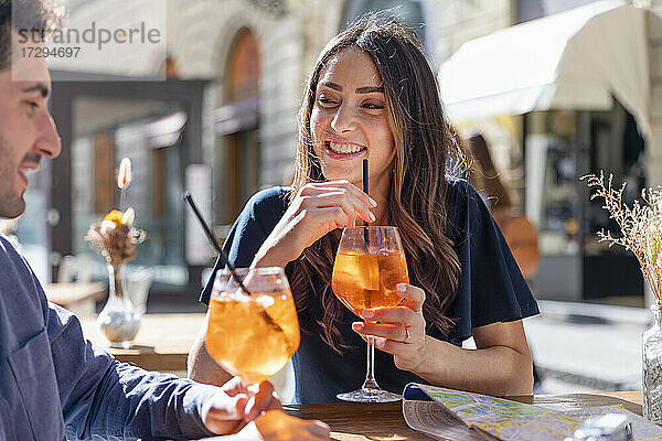 Lächelnde Frau mit Getränk  die einen Mann an einem sonnigen Tag ansieht