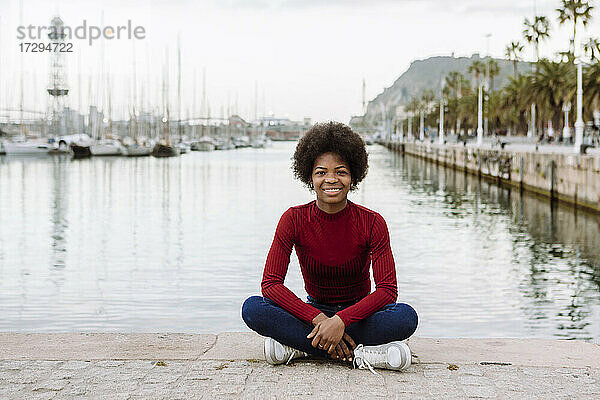 Junge Afro-Frau auf der Promenade in der Stadt sitzend