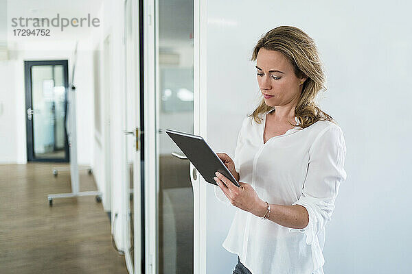 Geschäftsfrau mit digitalem Tablet bei schalldichter Kabine im Büro