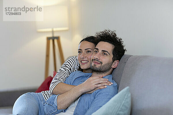 Lächelnde Paar Tag träumen zusammen  während auf dem Sofa im Wohnzimmer sitzen