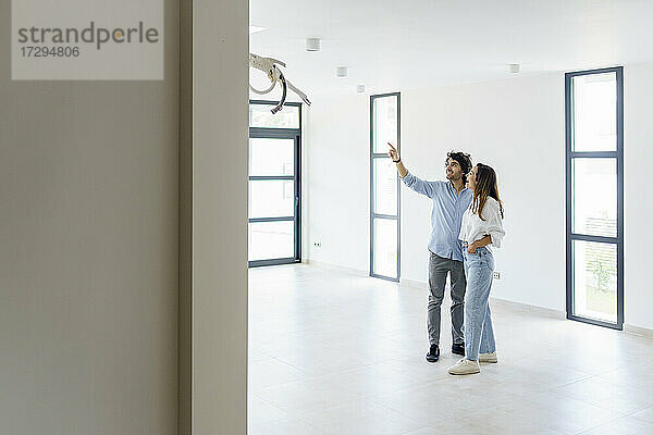 Mid adult man pointing while talking to girlfriend in new home