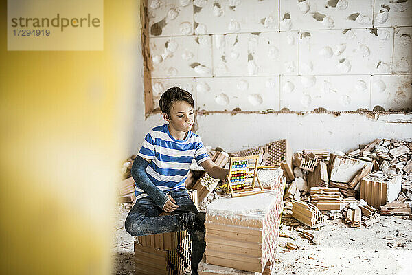 Junge zählt die Perlen des Abakus in einem Haus während der Renovierung