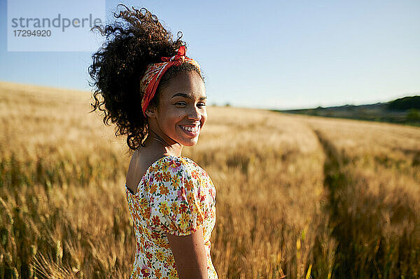Glückliche schöne Frau mit lockigem Haar in einem Weizenfeld