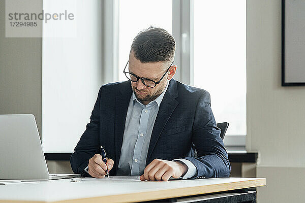 Geschäftsmann mit Brille bei der Vertragsunterzeichnung im Büro