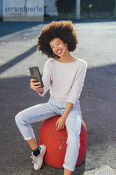 Lächelnde Frau  die ein Selfie mit ihrem Smartphone auf dem Fußweg macht
