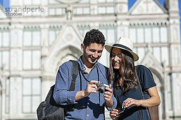 Lächelnde Touristen beim Überprüfen der Kamera mit der Basilika Santa Croce im Hintergrund in Florenz  Italien