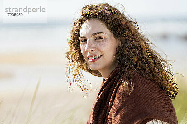 Schöne rothaarige Frau lächelnd am Strand während sonnigen Tag