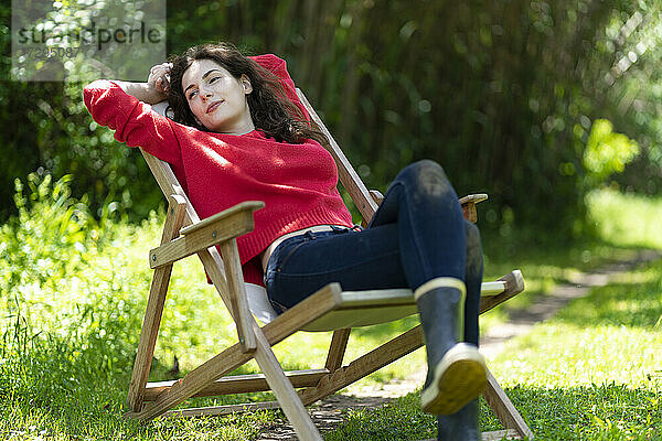 Junge Frau schaut weg und entspannt sich auf einem Stuhl im Garten