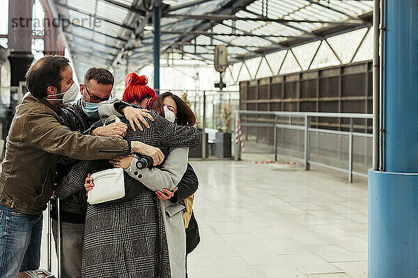 Freunde umarmen sich am Bahnhof während der COVID-19