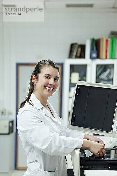 Lächelnde junge medizinische Expertin bei der Arbeit im Labor
