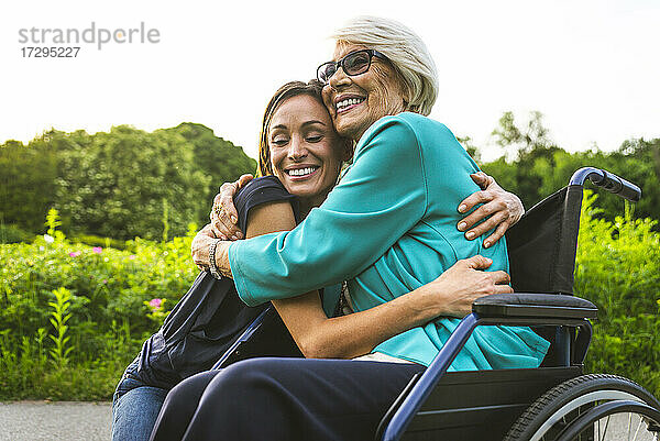 Glückliche Enkelin und Großmutter umarmen sich im Park