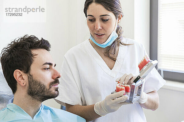 Eine Zahnärztin erklärt einem Patienten in einer medizinischen Klinik ein Zahnmodell