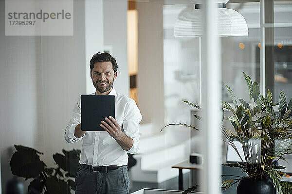 Männlicher Unternehmer  der ein digitales Tablet im Büro benutzt