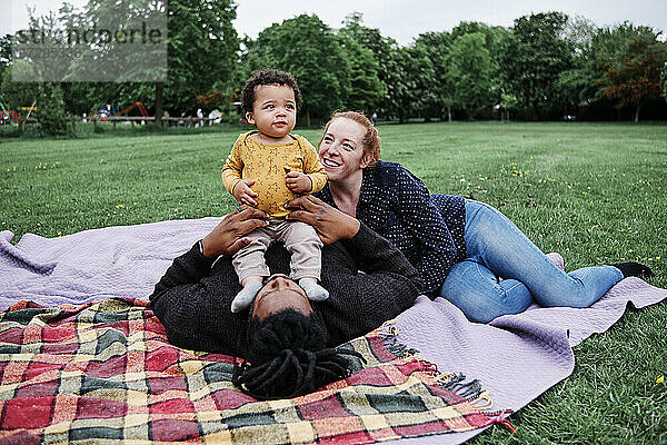 Glückliche Familie entspannt sich mit ihrem Sohn auf einer Picknickdecke im Park