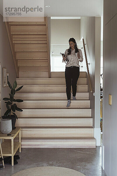 Geschäftsfrau geht die Treppe hinunter  während sie im Büro zu Hause arbeitet