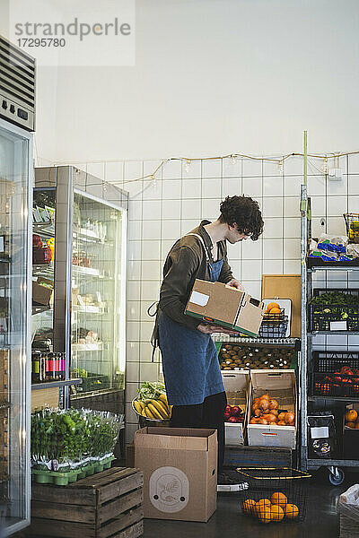 Männlicher Besitzer mit Obstkiste stehend im Laden