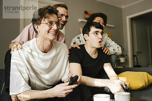 Glückliche männliche Freunde spielen Videospiel zu Hause