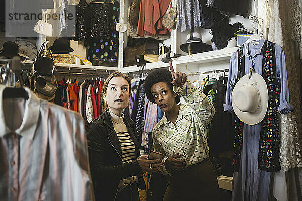 Afrikanische Besitzerin  die auf einen Kunden in einem Bekleidungsgeschäft zeigt