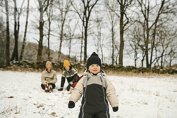 Mädchen mit Strickmütze schaut weg  während sie auf Schnee steht