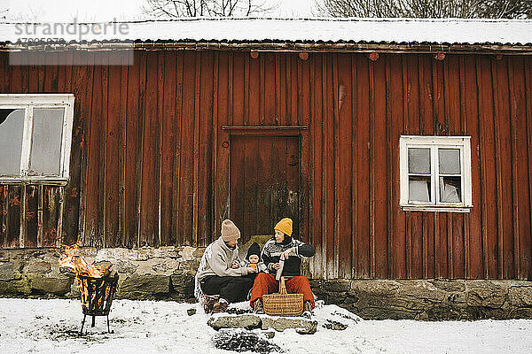 Lesbische Mütter mit Tochter gegen Hütte im Winter