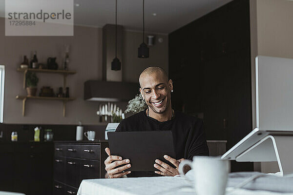 Lächelnder Geschäftsmann  der bei der Arbeit zu Hause ein digitales Tablet benutzt