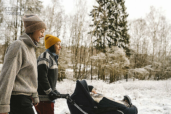 Reife Frau schiebt Baby-Kinderwagen beim Spaziergang mit Freundin im Winter