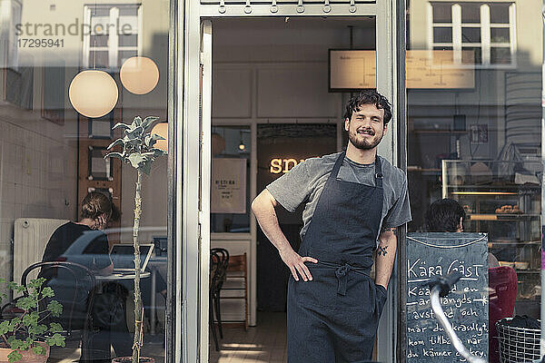 Porträt eines lächelnden männlichen Unternehmers  der am Eingang eines Cafés steht