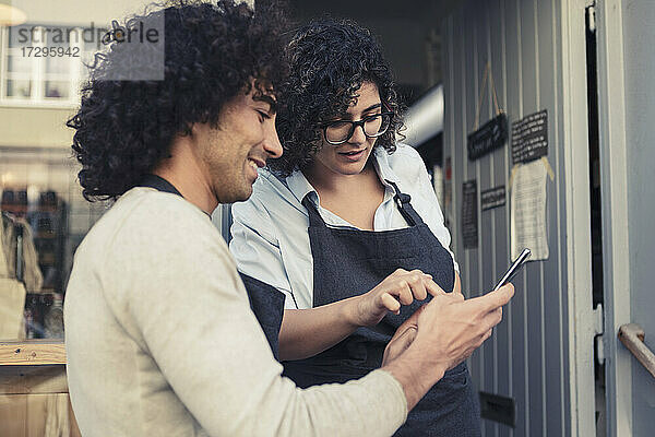 Weibliche und männliche Unternehmer benutzen ein Mobiltelefon  während sie an der Tür stehen