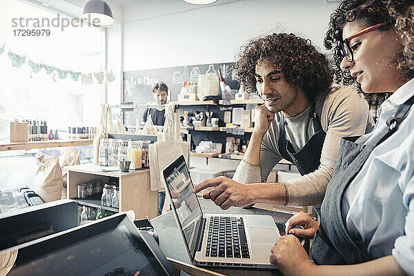 Männliche und weibliche Besitzer diskutieren über Laptop im Einzelhandelsgeschäft