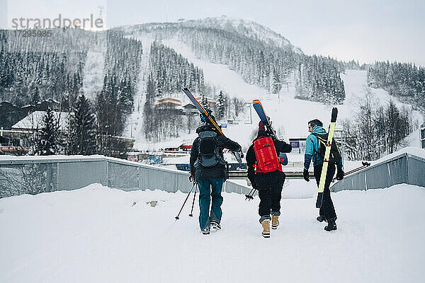 Rückansicht von weiblichen und männlichen Freunden zu Fuß auf Schnee im Skigebiet im Urlaub