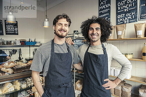 Porträt von glücklichen männlichen Mitbesitzern  die zusammen im Café stehen