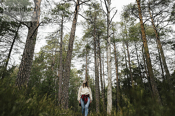 Junge Entdeckerin beim Wandern inmitten von Bäumen im Wald